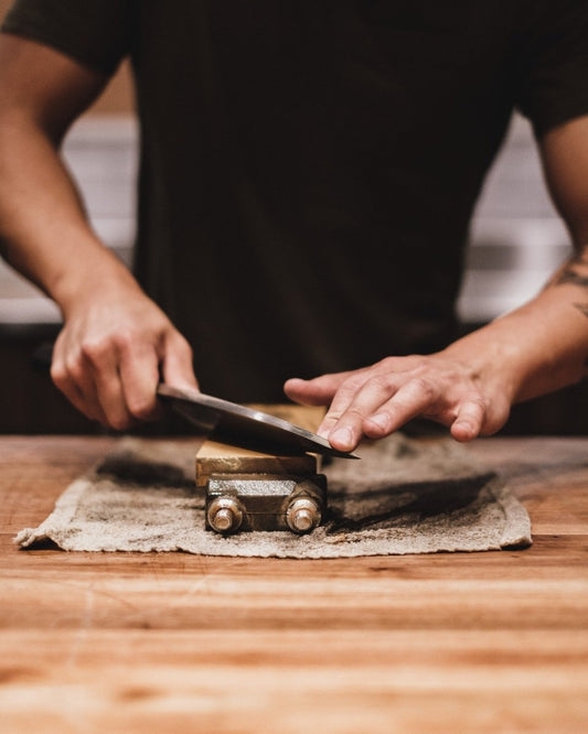 a man sharpening a kitchen knife with a whetstone