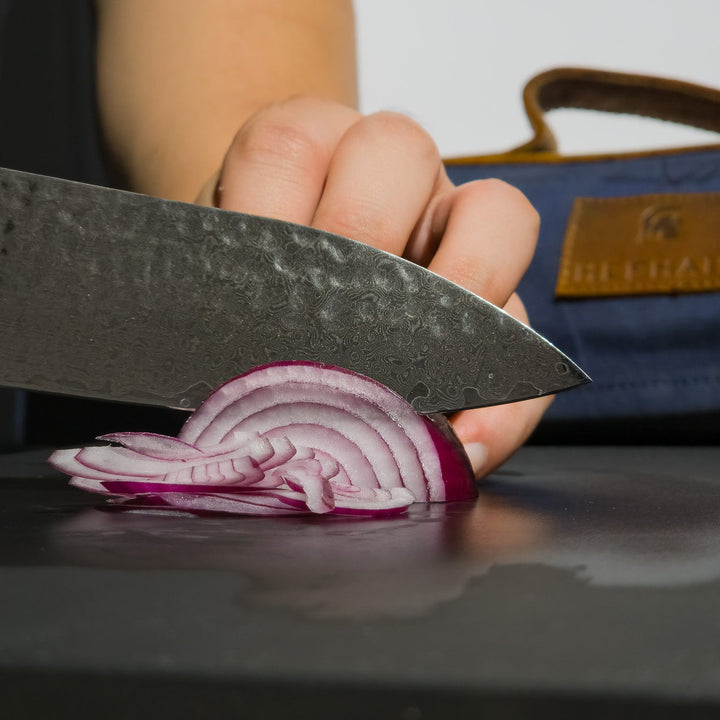 Chef knife slicing next to knife roll